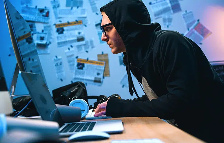 Imagen de un hacker con capucha trabajando en una computadora